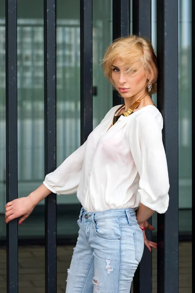 Outdoor estate moda splendido ritratto sulla bella giovane donna bionda sexy vestita con una camicia bianca e jeans strappati divertirsi in strada — Foto Stock