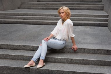 Açık yaz moda portre genç ve güzel sarışın seksi kadın üzerinde çarpıcı beyaz bir gömlek ve sokakta eğleniyor yırtık kot pantolon giymiş