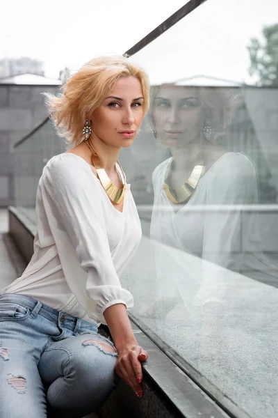 Utomhus sommar mode bedövning porträtt på ganska ung blond sexig kvinna klädd i en vit skjorta och trasiga jeans har kul på gatan — Stockfoto