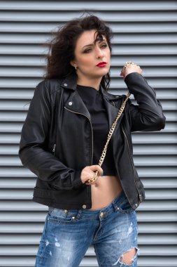 Çekici genç esmer kadın siyah deri ceket ve having fun şehirde onun elinde Altın zincir.