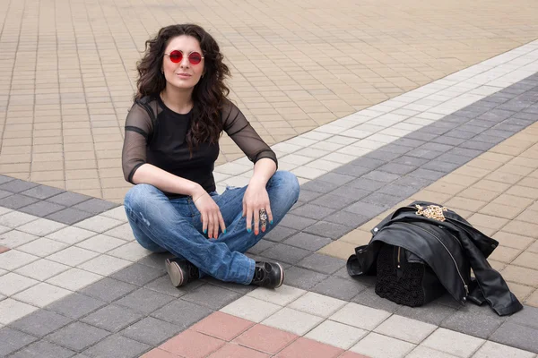 黒革のジャケットとサングラスの街で楽しく魅力的な若いブルネットの女性. — ストック写真