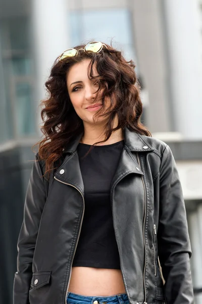 Glamorous young brunette woman in black leather jacket and sunglasses having fun in the city. — Stockfoto