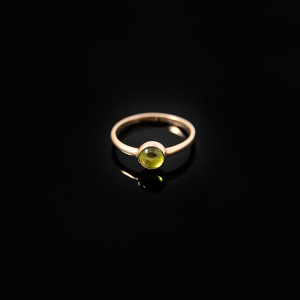 Luxusschmuck. Gelbgoldring mit grünem Edelstein auf schwarzem Hintergrund. Selektiver Fokus. — Stockfoto