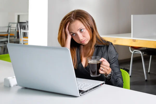 Depressed businesswoman sitting at computer. Tired and sleepy office worker looking at the laptop screen and needs help.