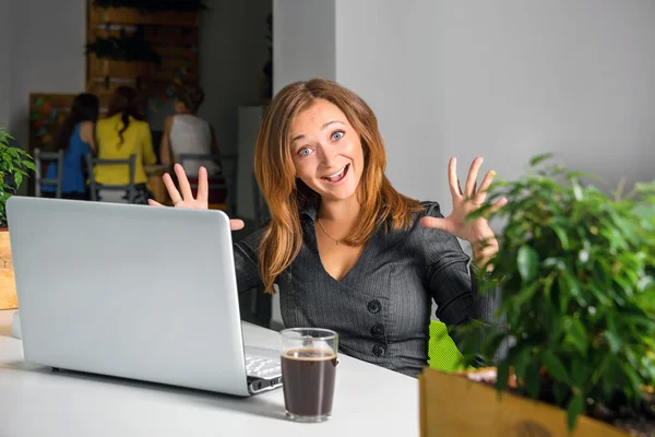 Excited happy businesswoman with raised arms sitting at the table with laptop celebrating her success. Funny image of winner or surprised office worker. Green eco office concept. — Stock Photo, Image