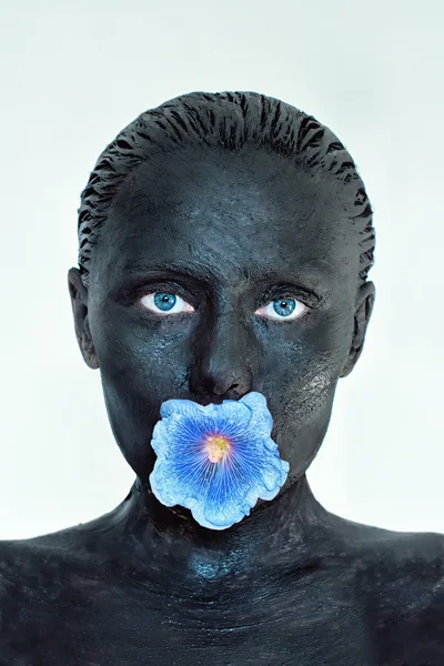 Hautpflege. Frau in Lehmmaske auf Gesicht, Ohren und Schultern mit blauer Blume im Mund isoliert auf weiß. Schönheitsbehandlung und Wellness-Konzept. — Stockfoto