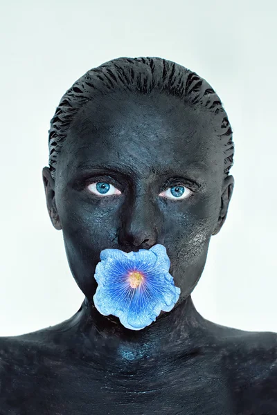 Cura della pelle. Donna in argilla maschera di fango sul viso, sentire e spalle con fiore blu in bocca isolato su bianco. Trattamento estetico e concetto spa . — Foto Stock