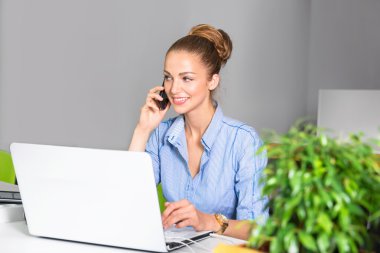 İş, teknoloji ve yeşil office kavramı - ofisinde telefonda konuşurken dizüstü bilgisayar ile genç başarılı işkadını. Tablet bilgisayar kullanan güzel kadın.