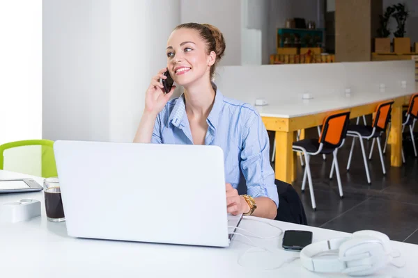 Business, technology and green office concept - young successful businesswoman with laptop computer talking on the phone at office. Beautiful woman using tablet computer.