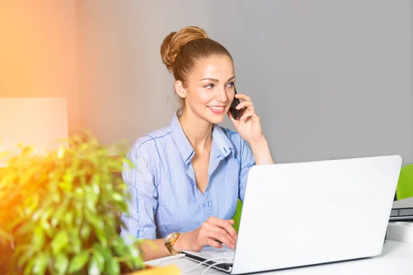 Επιχειρήσεων, τεχνολογίας και πράσινο έννοια γραφείο - νέοι επιτυχημένη επιχειρηματίας με φορητό υπολογιστή που μιλάτε στο τηλέφωνο στο γραφείο. Όμορφη γυναίκα που χρησιμοποιούν τον υπολογιστή tablet. — Φωτογραφία Αρχείου
