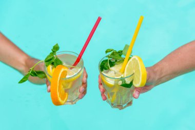 Mavi bir havuz üzerinde meyve ve nane ile süslenmiş renkli kokteyller. Rahatlık, yaz tatili ve tropikal tatil atmosferlerini tasvir etmek için mükemmel..