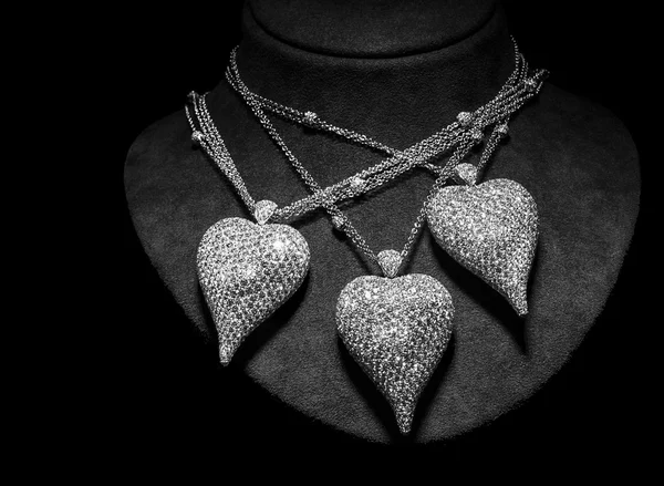 Drie kettingen zijn gemaakt van wit goud of zilver op een stand. Hart-vormige Hangers met diamanten. Luxe vrouwen accessoires. — Stockfoto