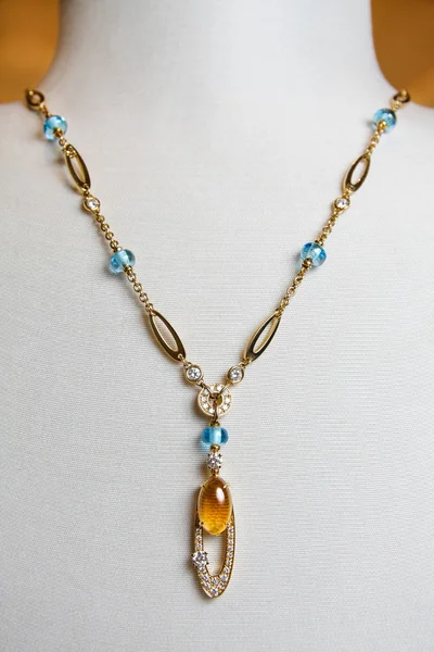 Collar de lujo de oro amarillo con diamantes y preciosas gemas de colores en un soporte . — Foto de Stock