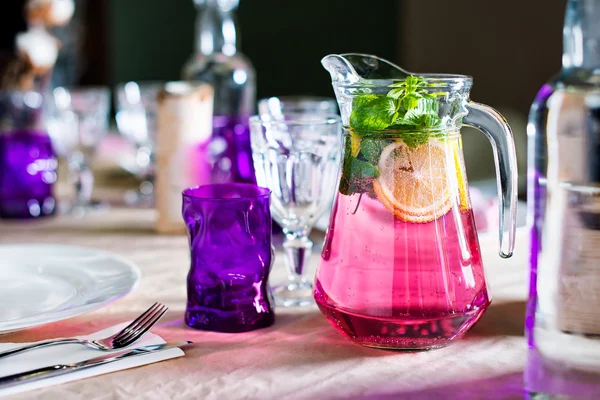 Meyveli içecek nane ve limon akşam yemeği için hazır bir şekilde dekore edilmiş bir tablo ile bir sürahi. Düğün için tablo kümesi veya başka bir olay restoranda güzel dekore edilmiş.