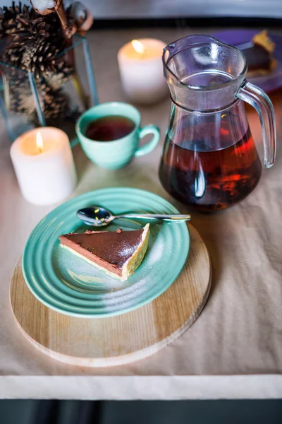 Bucată de tort delicios cu spumă de ciocolată pe placă colorată pe fundal de masă din lemn. Setarea mesei pentru petrecerea ceaiului. Focalizare selectivă . — Fotografie, imagine de stoc