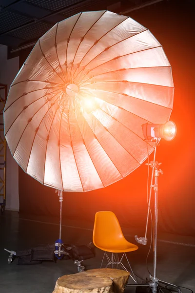 Empty photo studio with modern interior and lighting equipment. Preparation for studio shooting: empty chair and studio lighting.