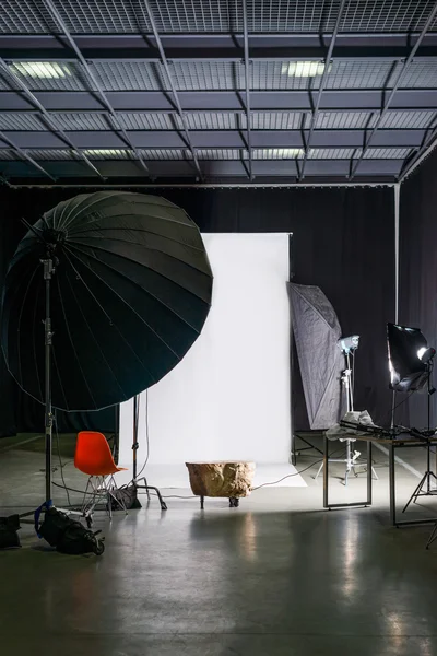 Порожня фотостудія з сучасним інтер'єром та освітлювальним обладнанням. Підготовка до студійної зйомки: порожнє крісло і студійне освітлення . — стокове фото