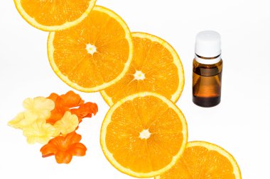 Bottle of aromatic essence and fresh orange slices on white.