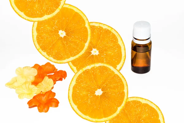 Бутылка ароматной сущности и свежие апельсиновые ломтики на белом . — стоковое фото