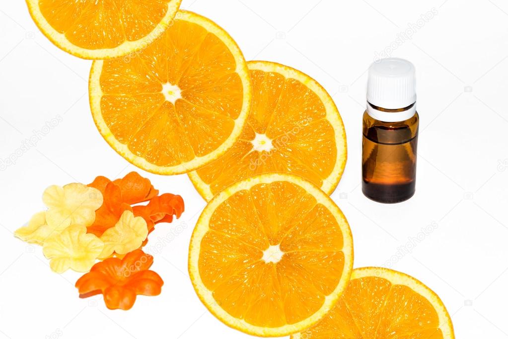 Bottle of aromatic essence and fresh orange slices on white.