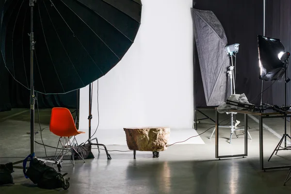 Tom fotostudio med modern interiör och belysningsutrustning. Förberedelse för studio fotografering: tomma stol och studio belysning. — Stockfoto