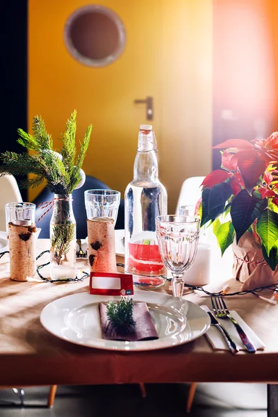 Decorated Christmas holiday table ready for dinner. Beautifully decorated table set with candles, spruce twigs, plates and serviettes for event in the restaurant.