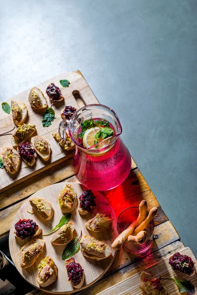 Una jarra de bebida afrutada con menta y limón y bandeja de madera de aperitivos en un banquete en una mesa de té decorada. Mesa bellamente decorada en el restaurante . —  Fotos de Stock