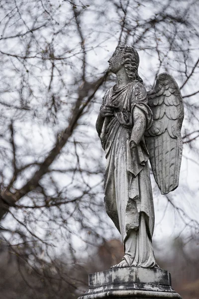 Oude grafsteen sculptuur van een engel met gebroken arm en vleugels op de begraafplaats. — Stockfoto