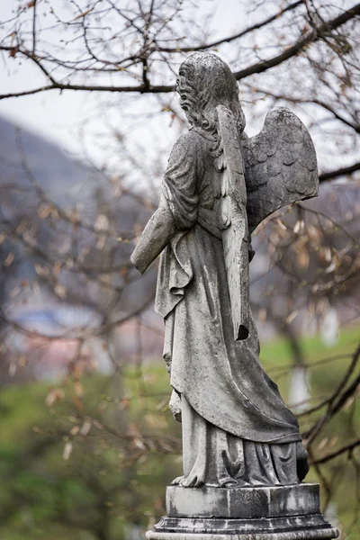 Antigua escultura de lápida de un ángel con el brazo roto y alas en el cementerio . — Foto de Stock