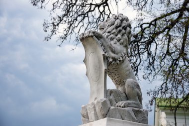 Bir kalkan içinde onun paws tutan aslan heykeli. Regal aslan üzerinde boş hanedan kalkan yaslanmış.