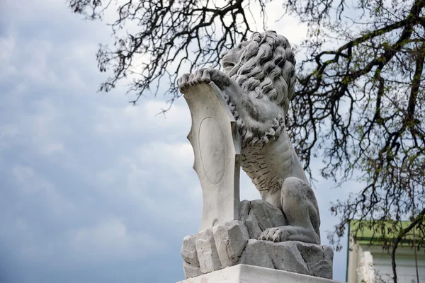 Staty av lejon håller en sköld i tassarna. Regal lion lutar på Tom heraldiska skölden. — Stockfoto