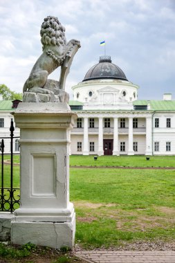 Statue of lion holding a shield in its paws. Regal lion leaning on empty heraldic shield near the castle entrance. The palace and park complex Manor Tarnowski, s.Kachanovka, Ukraine.