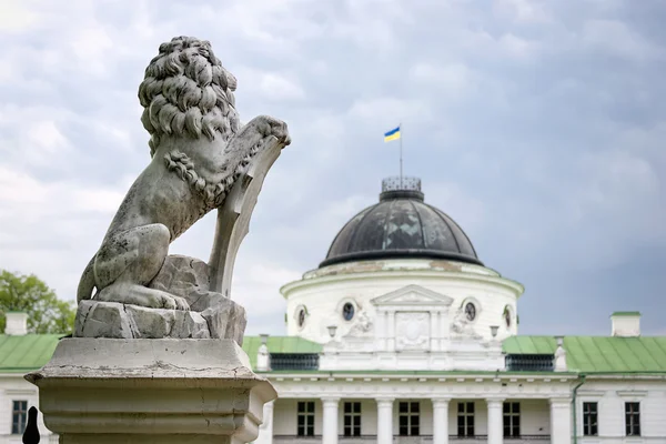 Statua di leone che tiene uno scudo nelle zampe. Leone reale appoggiato su uno scudo araldico vuoto vicino all'ingresso del castello. Il palazzo e parco complesso Manor Tarnowski, s.Kachanovka, Ucraina . — Foto Stock