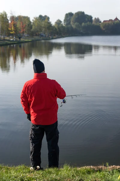 Homem pescando em um lago ao pôr do sol . — Fotografia de Stock