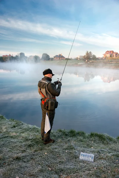 Homem pescando em um lago ao pôr do sol . — Fotografia de Stock