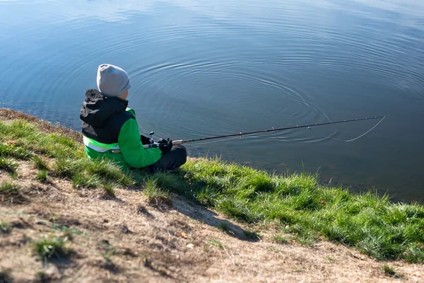 Littile boy pesca em um lago ao pôr-do-sol. Visão traseira . — Fotografia de Stock