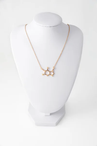 Ketting in de vorm van cafeïne molelule gemaakt van goud op witte stand. Luxe vrouwen accessoires. — Stockfoto