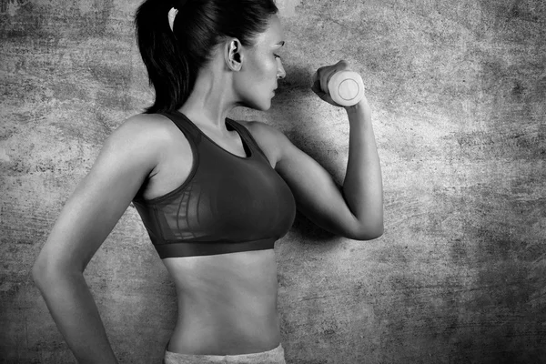 Spor salonunda bir beton duvar arka plan üzerinde ağırlıkları ile egzersiz kadın uygun. Sağlıklı yaşam konsepti. — Stok fotoğraf
