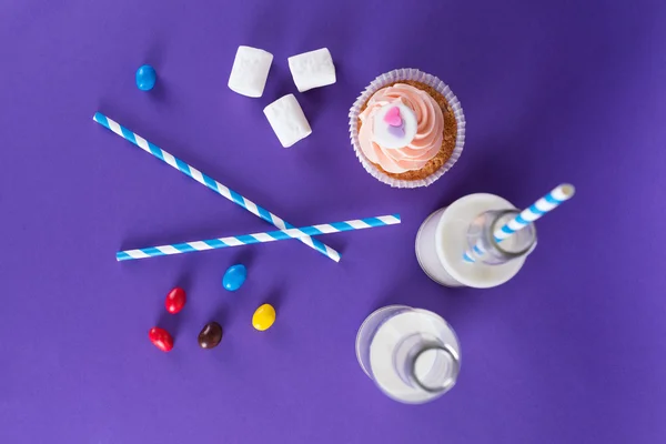 Cupcake for Valentine's Day with hearts on top of whipped cream and milk cocktails with retro cocktail tubes, served in bottles on colourful background. — Stock Photo, Image