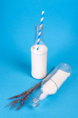 Milk cocktails with retro cocktail tubes, served in bottles on colorful background with lavender.