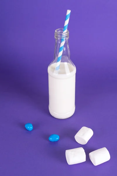 Молочний коктейль з ретро-коктейльною трубкою, подається в пляшці на барвистому фоні з солодким зефіром . — стокове фото