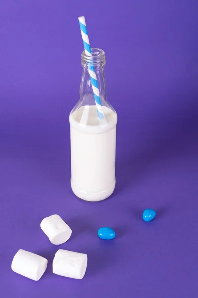 Cocktail au lait avec tube à cocktail rétro, servi en bouteille sur fond coloré avec guimauves sucrées . — Photo