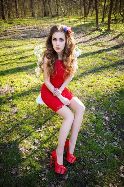 Beautiful young woman in summer garden sitting on a chair with roses. Beauty summertime. — Stock Photo, Image