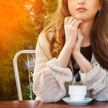 Beautiful young woman drinking hot coffee in summer garden.