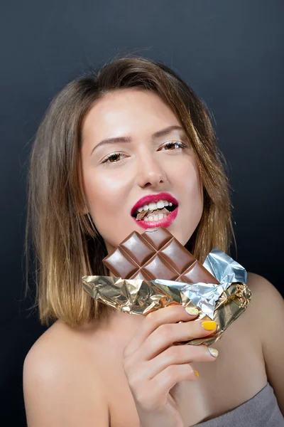 Hermosa joven rubia comiendo barra de chocolate . — Foto de Stock