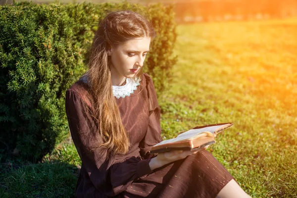 庭の草の上に座って本を読んでロマンチックな若い女性。屋外時間の概念をリラックス. — ストック写真