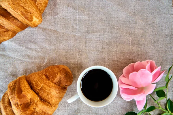 French breakfast on a linen background. Croissant with coffee and rose.