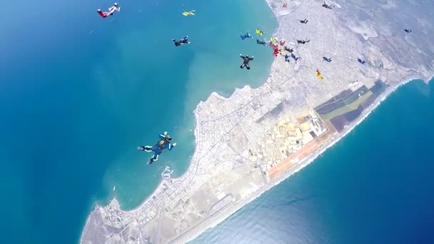 Группа парашютистов зависает в ускоренном свободном падении над прибрежным городом — стоковое видео