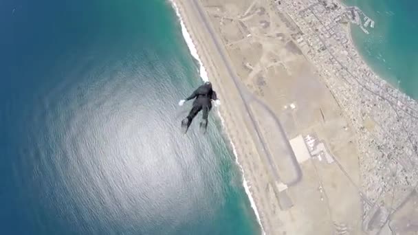 Skydiver is flying by in accelerated free fall above coastal city — Stok video