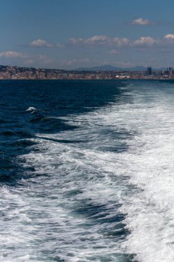 İtalya 'nın Napoli kıyı şeridinden deniz manzarası. Büyük yolcu gemileri limanda, güneşli havada şehir manzarası mavi gökyüzü ve beyaz bulutlarla.